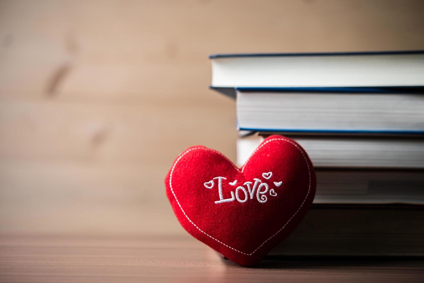 corazón rojo y libro sobre mesa de madera foto