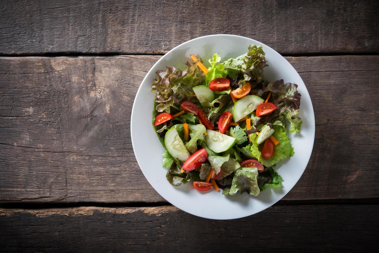 Ensalada de verduras frescas sobre fondo de madera foto