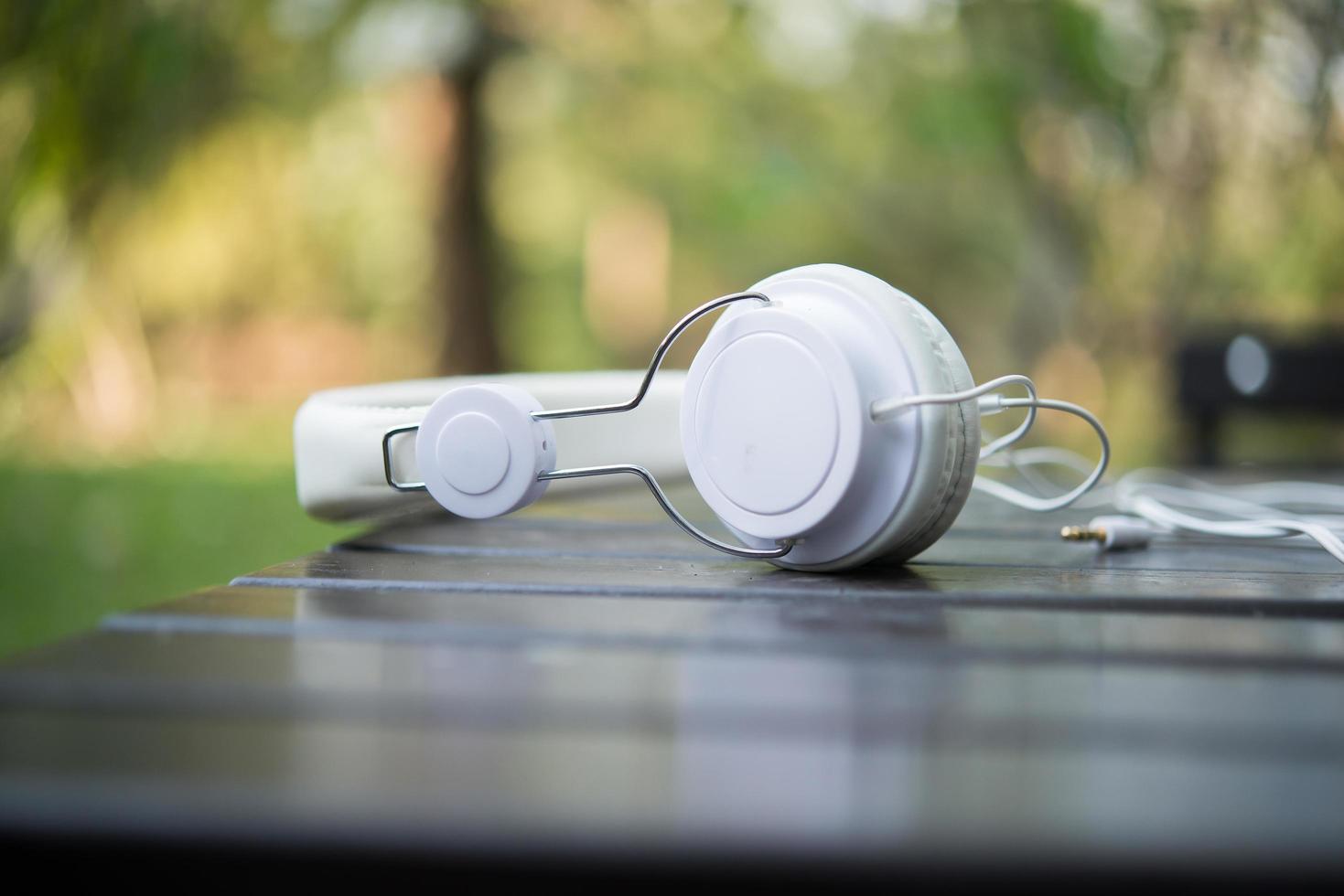 White headphones on wooden table with nature background photo