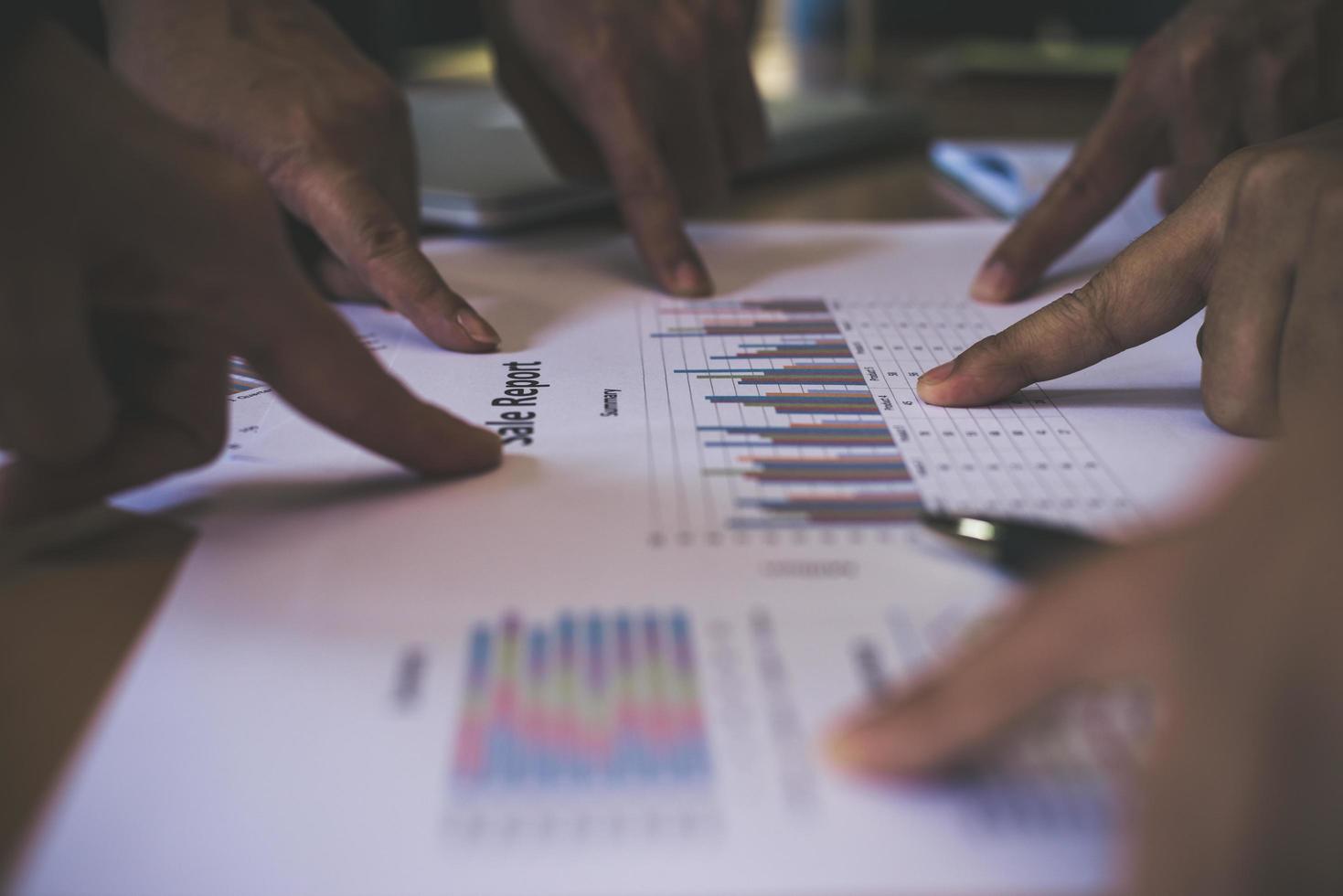 Group of business partners pointing to graph sheet photo