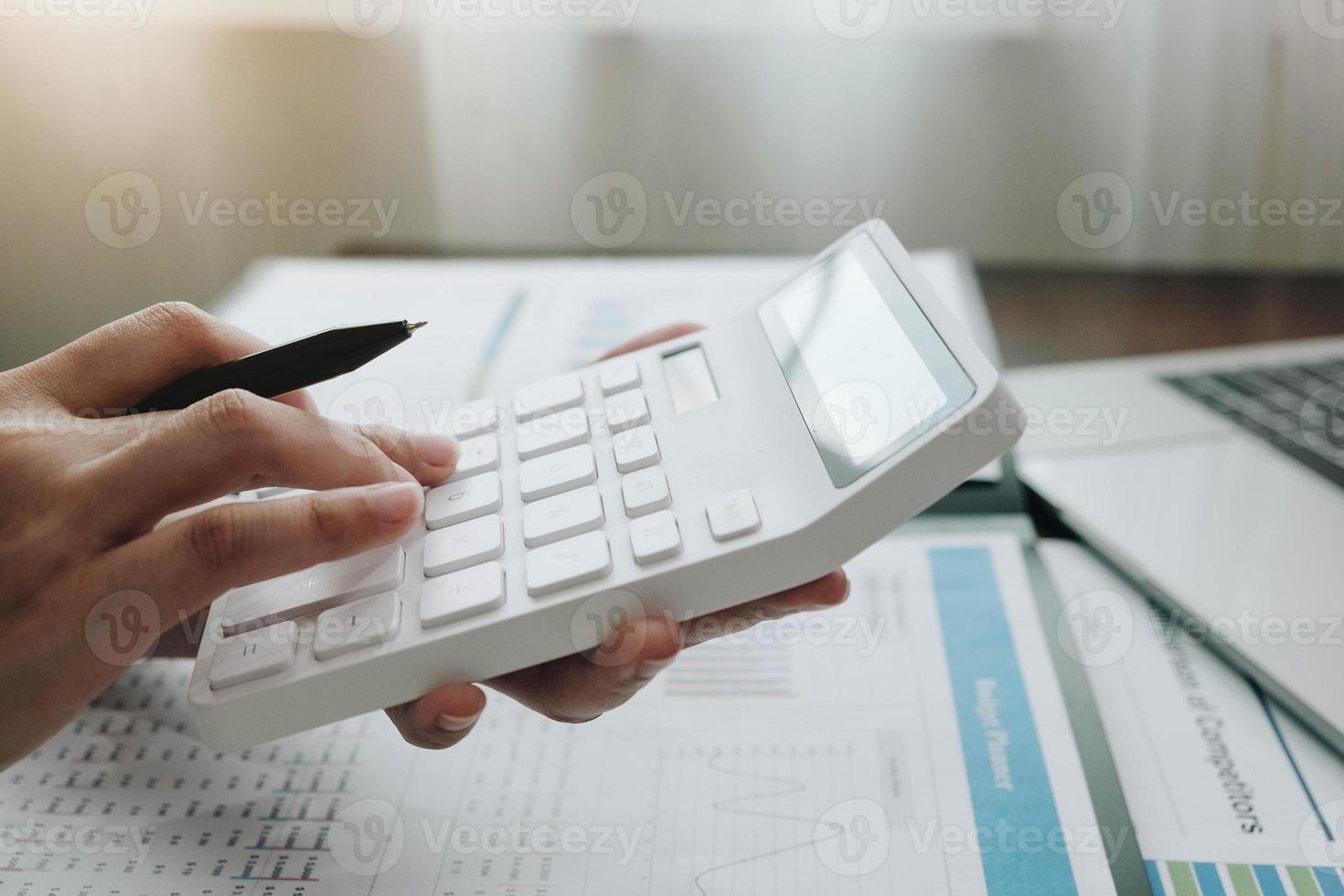 Business woman using a calculator and laptop photo