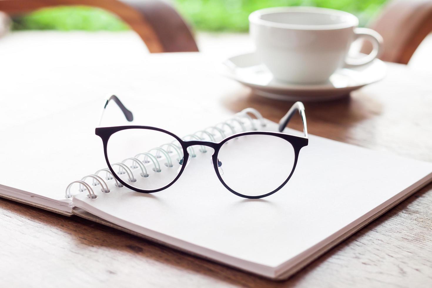 Open notebook and eyeglasses with a cup of coffee photo