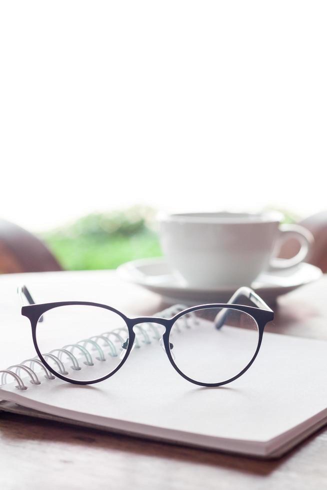 Glasses on a notebook with a coffee photo