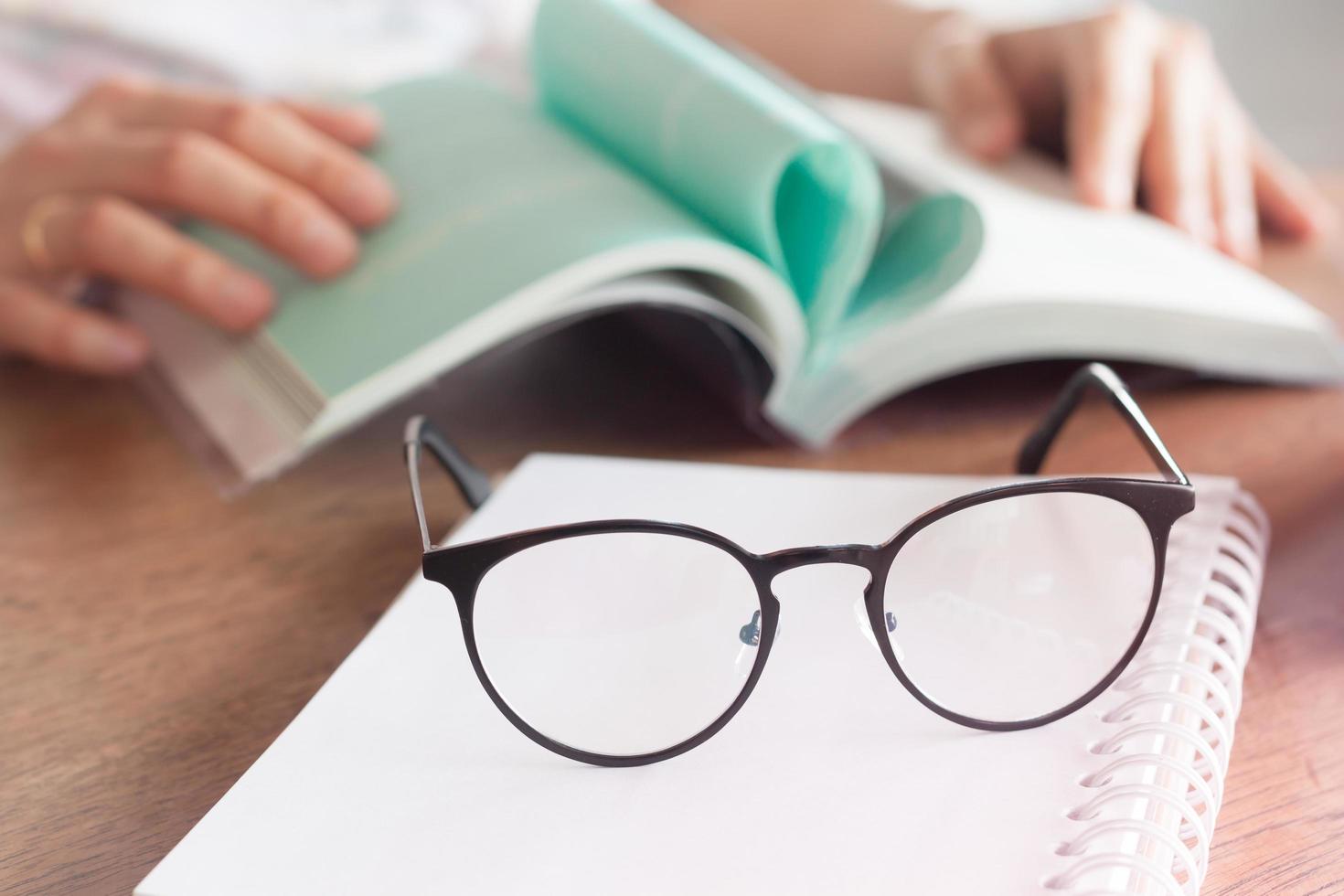 Glasses on a notebook with a book in the background photo