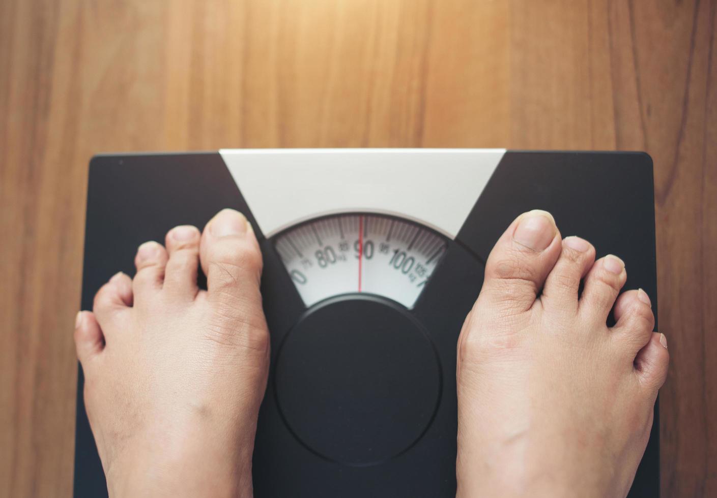 Woman's feet standing on weight scale photo