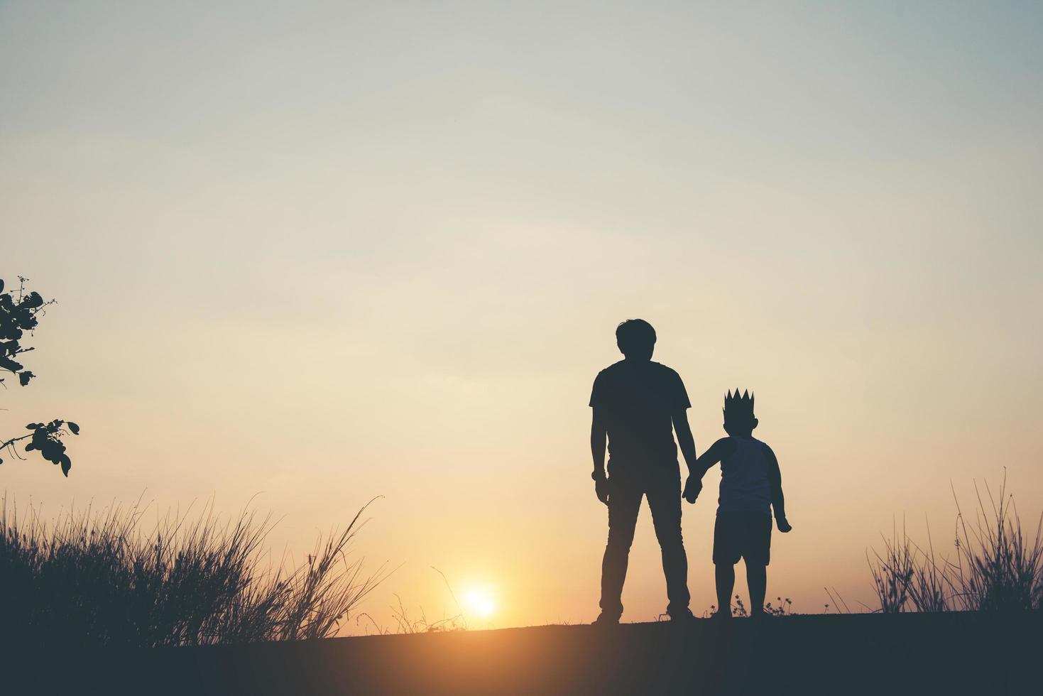 Silhouette of father and son standing together photo