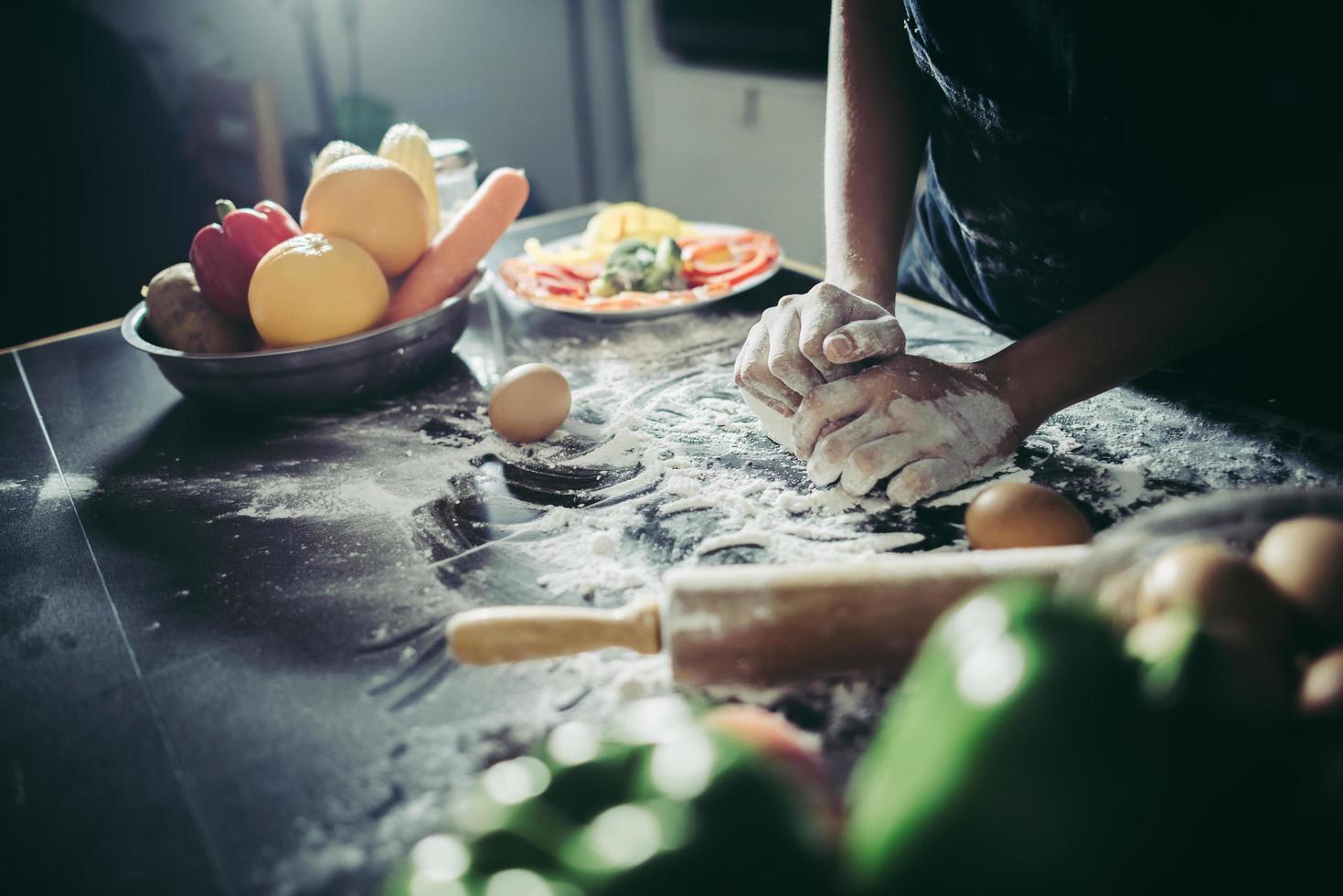 Woman kneads dough for pizza photo