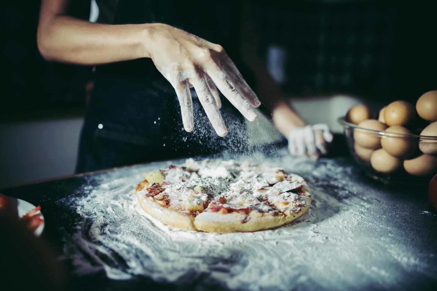 Chef's hands pouring flour on raw dough photo