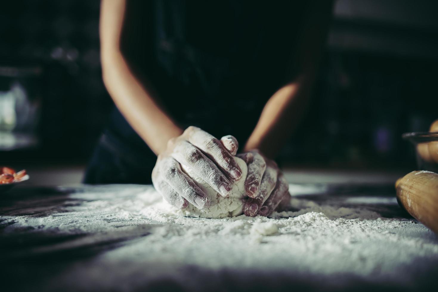 Woman kneads dough for pizza photo