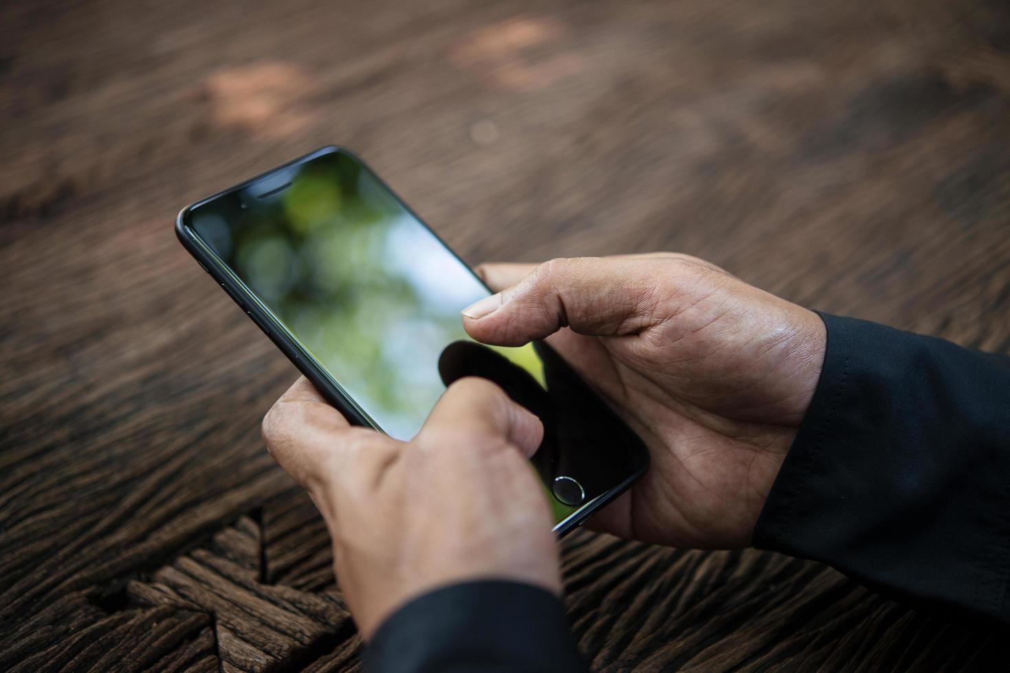 Person holding smart phone at a table photo