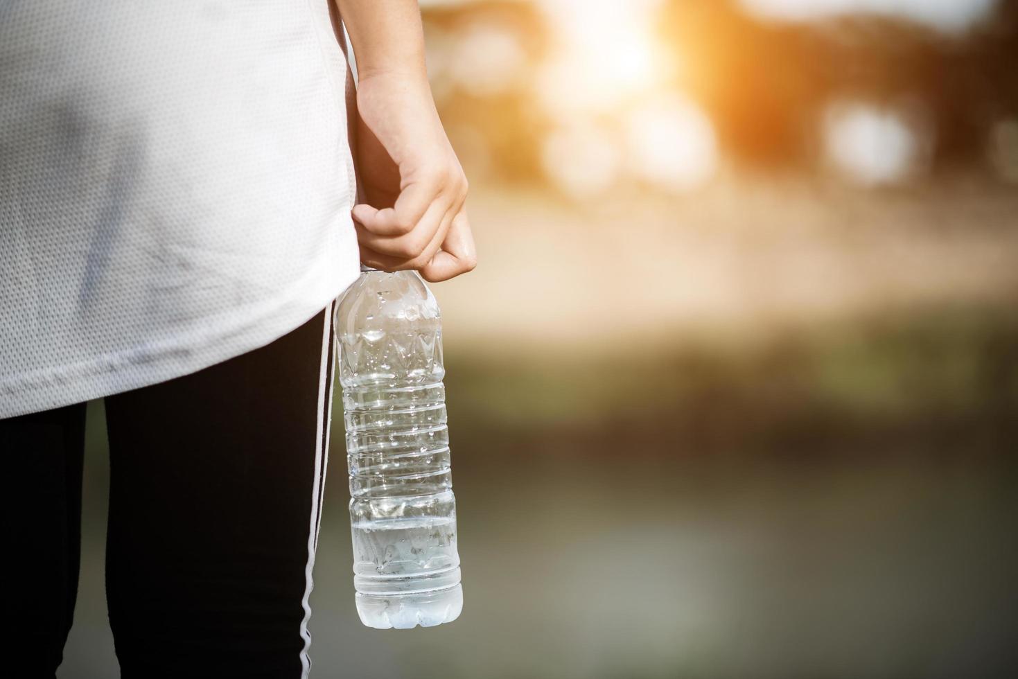 Colocar joven mujer sosteniendo una botella de agua después de correr foto