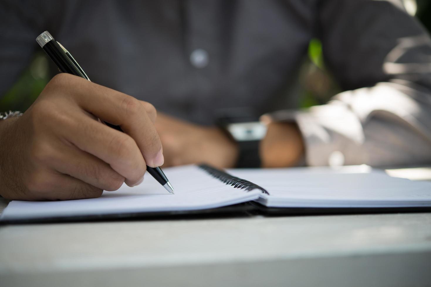 Hombre escribiendo en el bloc de notas mientras está sentado relajándose en el jardín de su casa foto