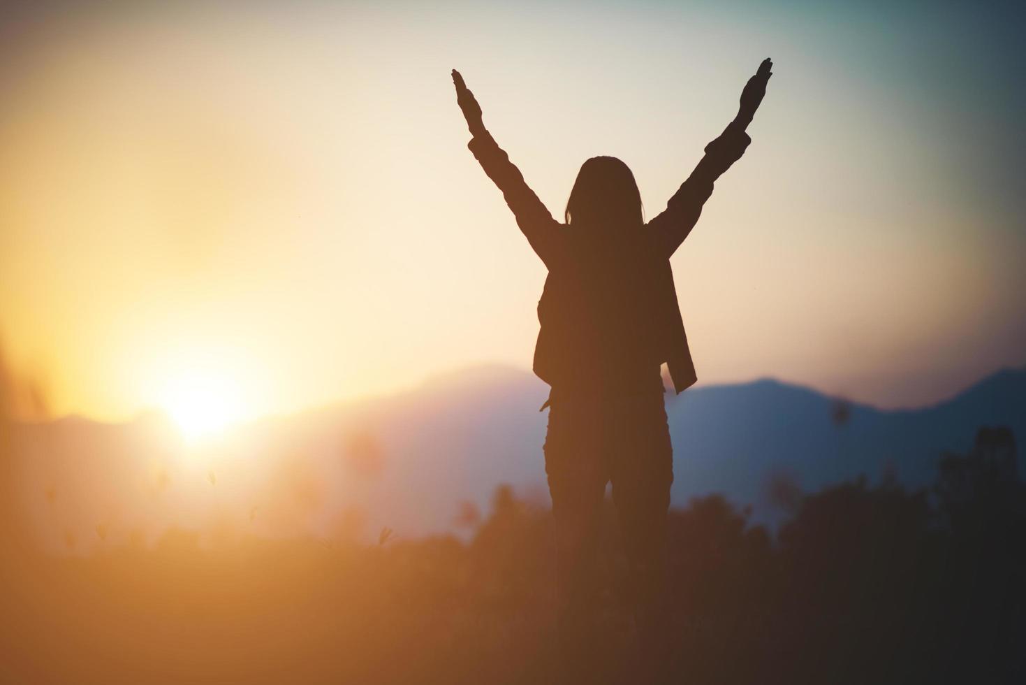 Silhouette of a woman praying over a beautiful sky background photo