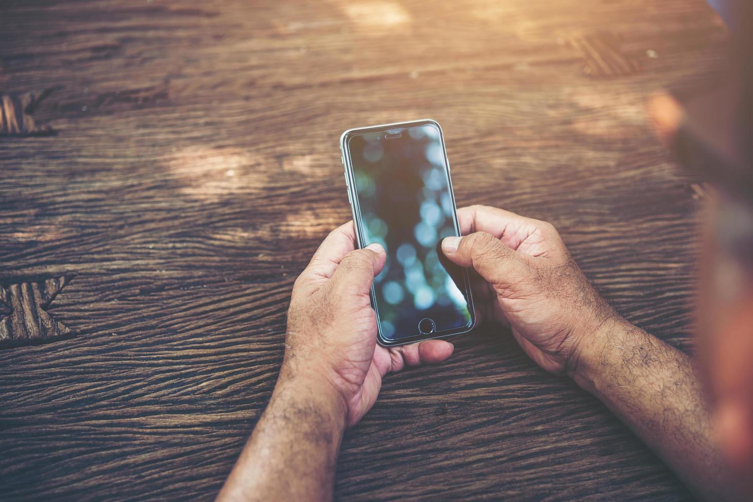 Person holding smart phone at a table photo