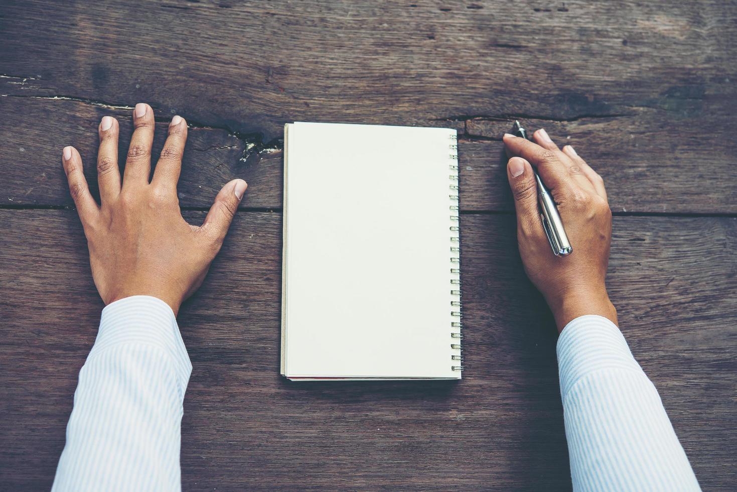 Man writing on blank notebook on wooden table photo