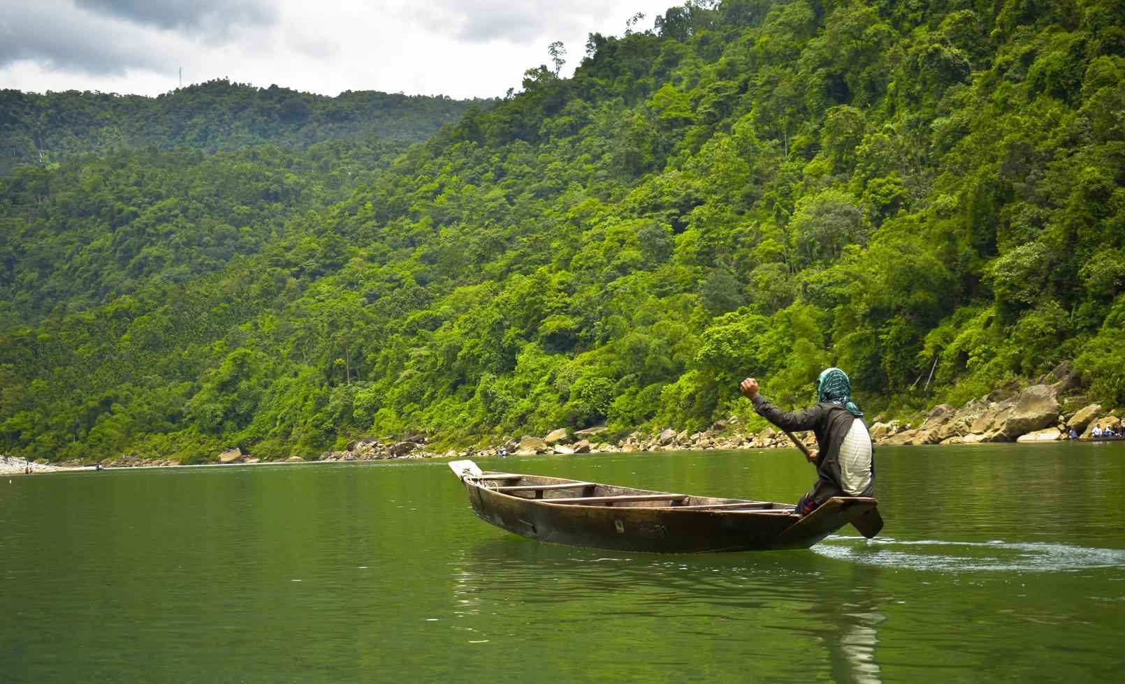 Los hombres remando en un bote cerca de Green Hill durante el día foto