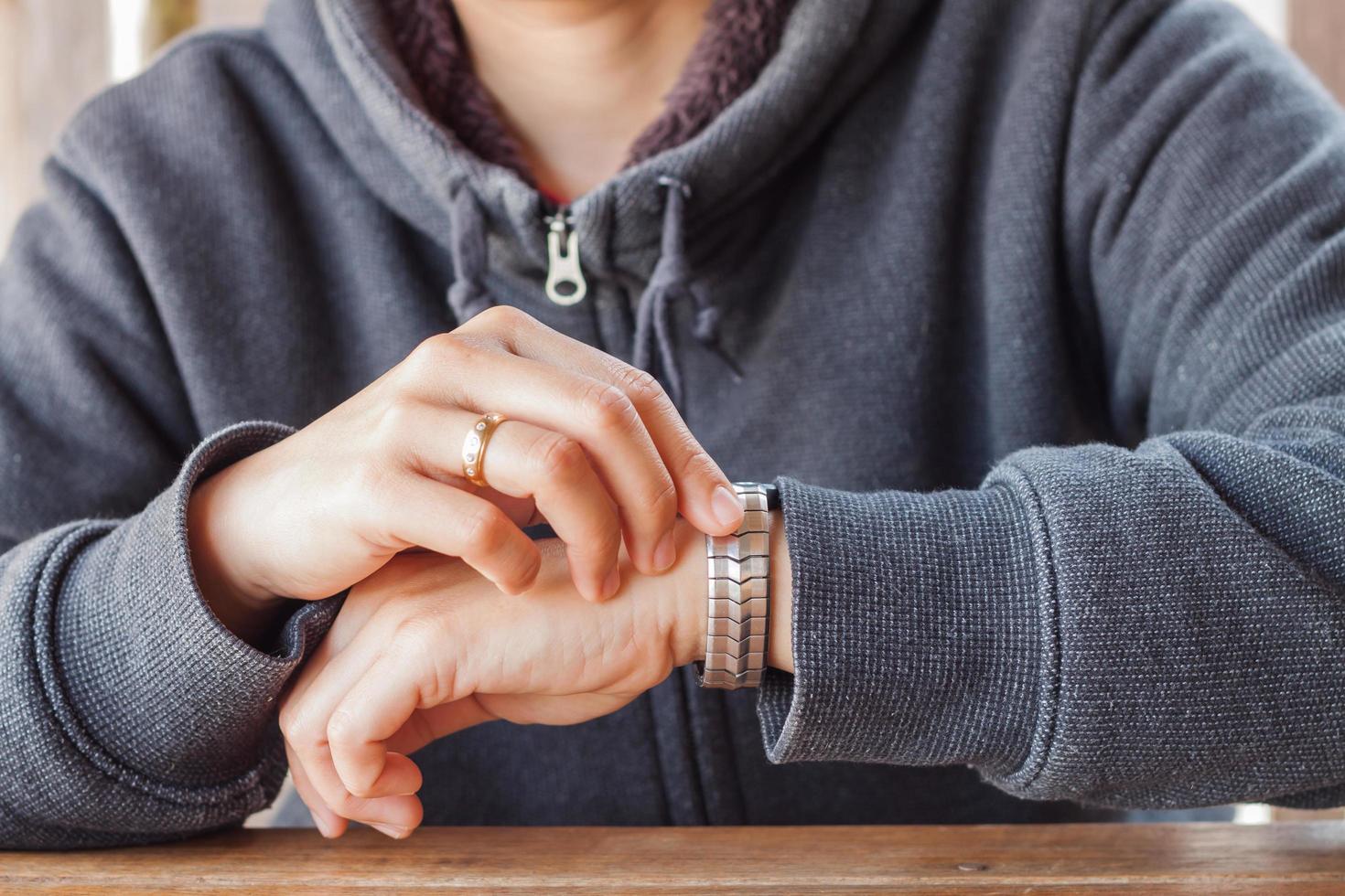 Person wearing a hoodie and checking the time photo