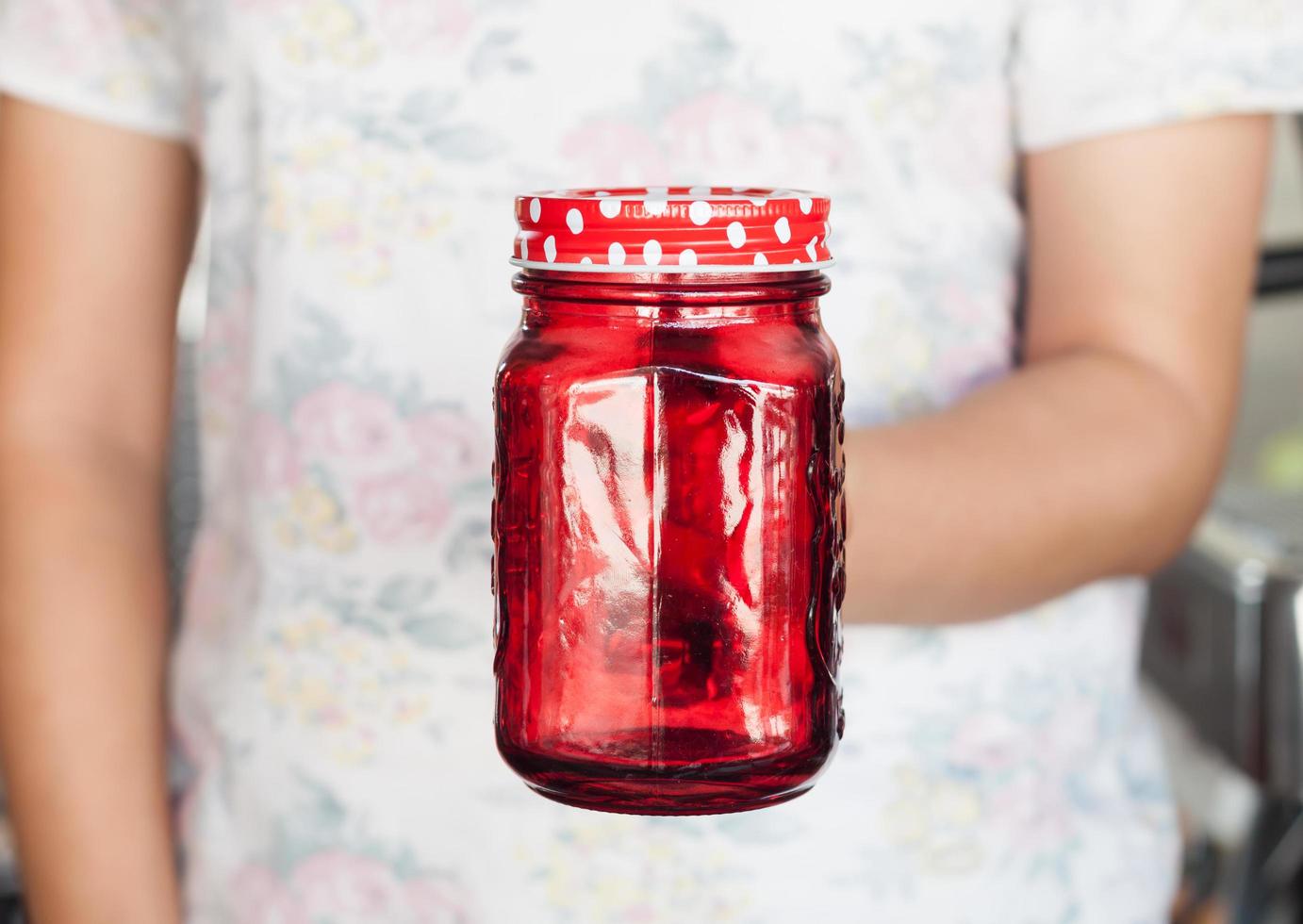 Person holding a red glass jar photo