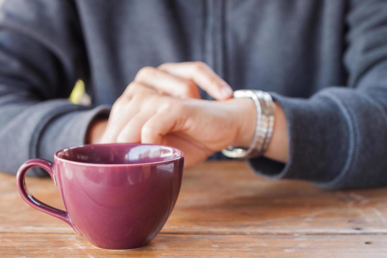 persona que controla la hora con una taza de café foto