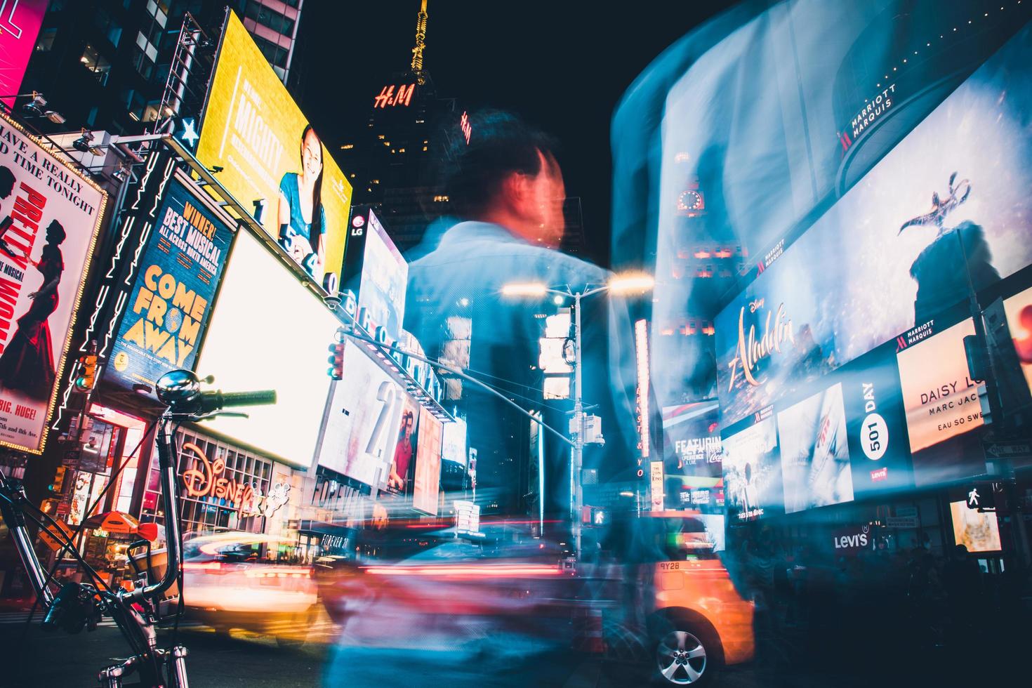 Man in blue shirt standing near cars during night time photo