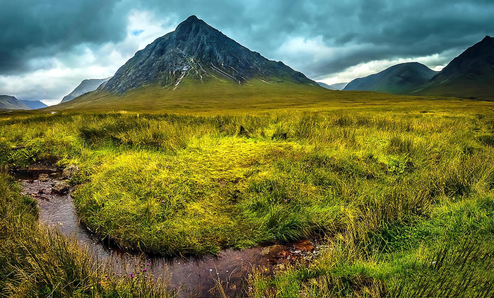 Mountains and a grass field under a cloudy sky photo