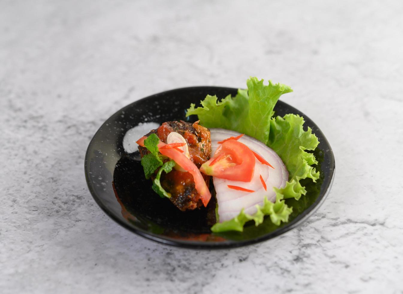 Plato de sardina picante en cuenco de cerámica negra foto