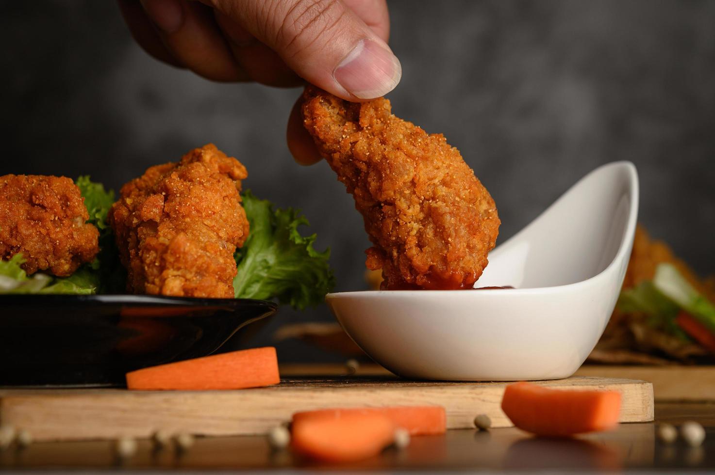 Hand dipping crispy fried chicken into sauce photo