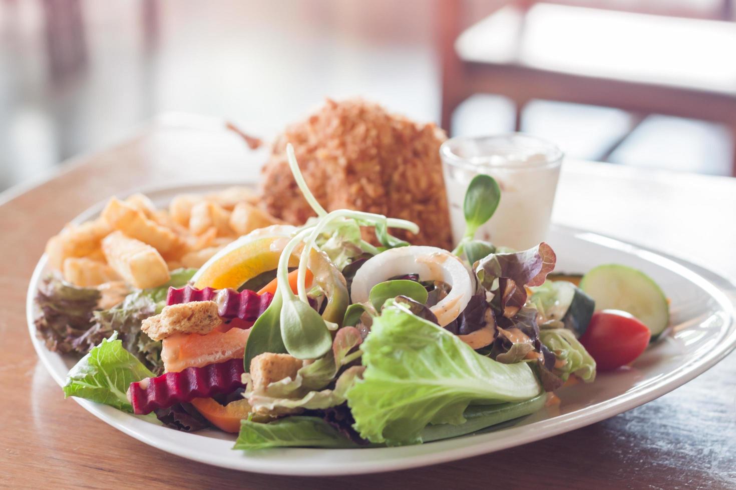 plato de ensalada con pescado frito y patatas fritas foto