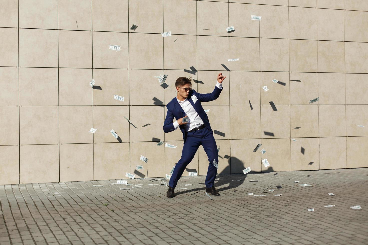 Man in a suit dancing in money photo