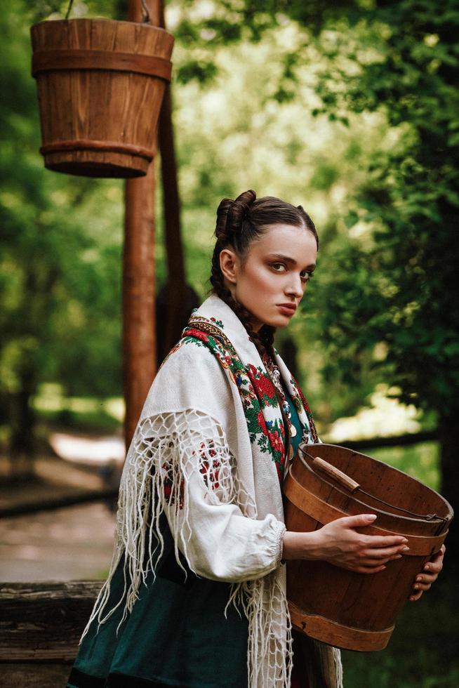 niña ucraniana en un traje tradicional con un cubo en sus brazos foto