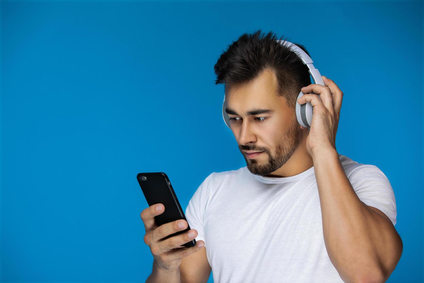 Hombre europeo viendo algo en su teléfono y escucha auriculares foto