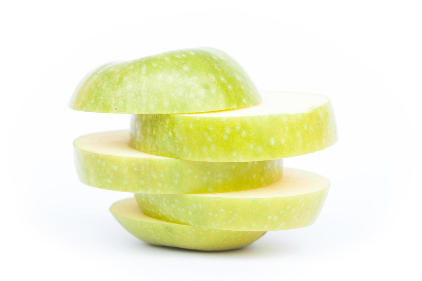 Close-up de una manzana verde en rodajas sobre un fondo blanco. foto