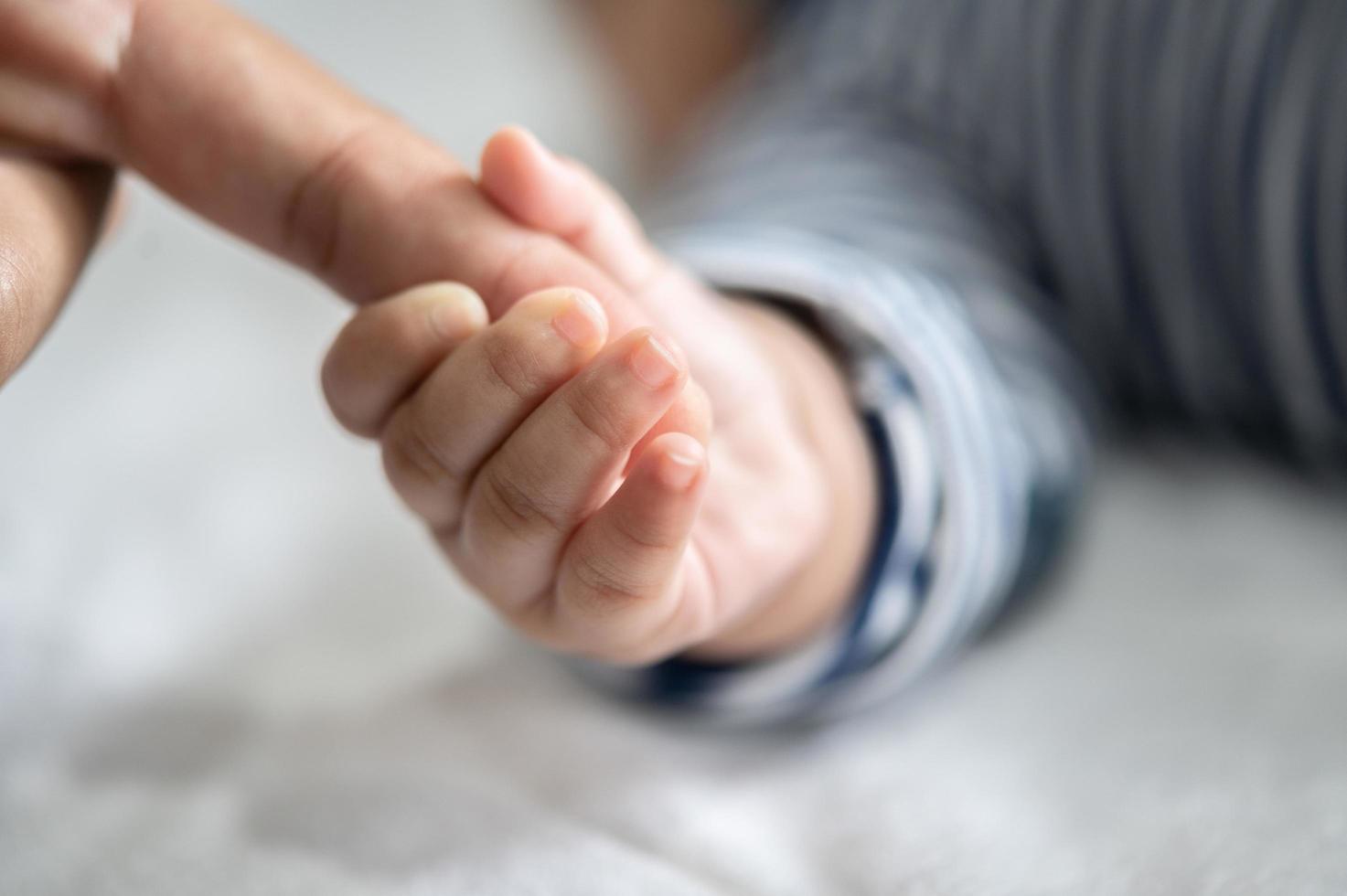 The hand of the newborn baby holds the fingers of the mother photo