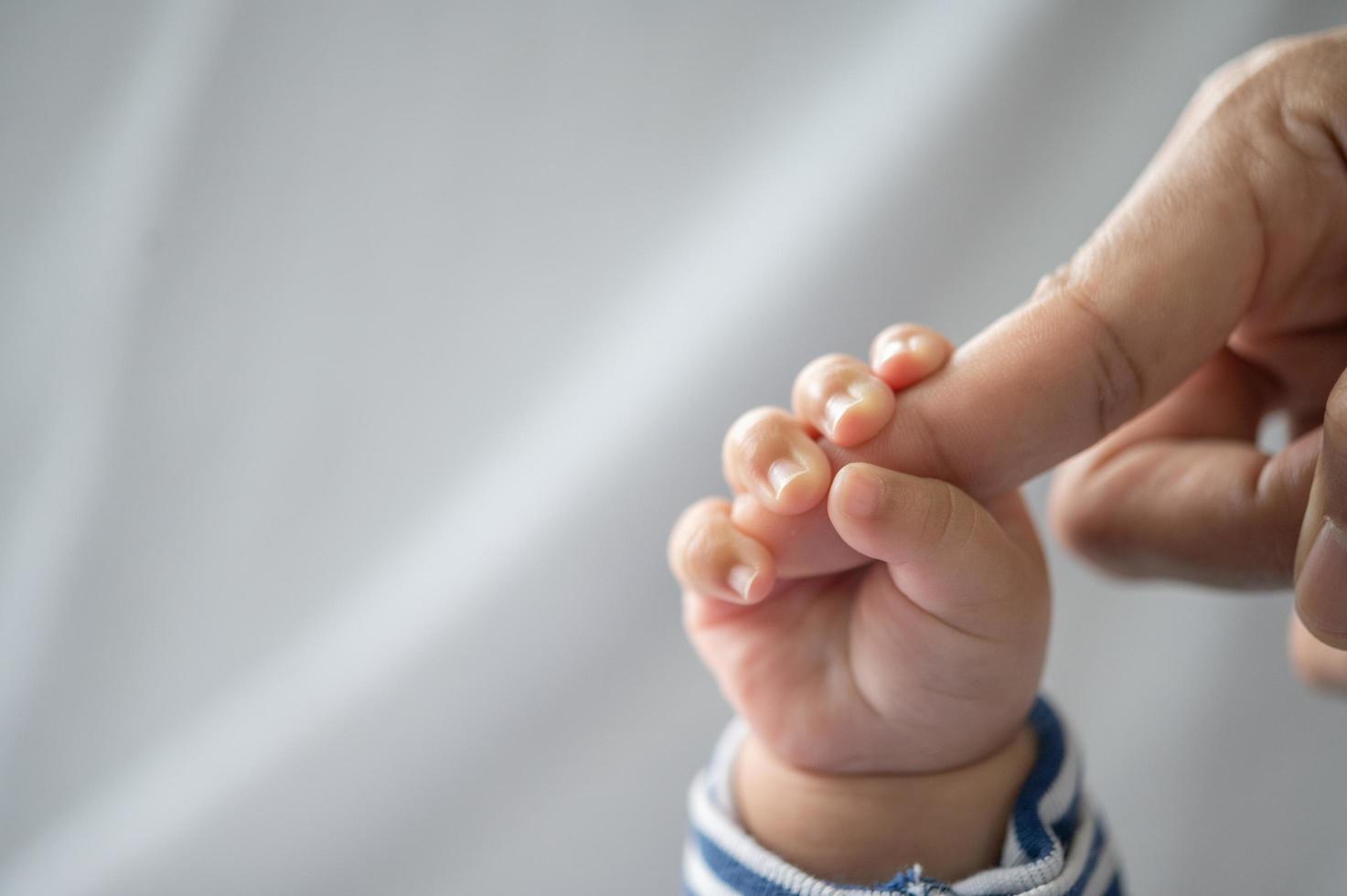 The hand of the newborn baby holding the fingers of the mother photo