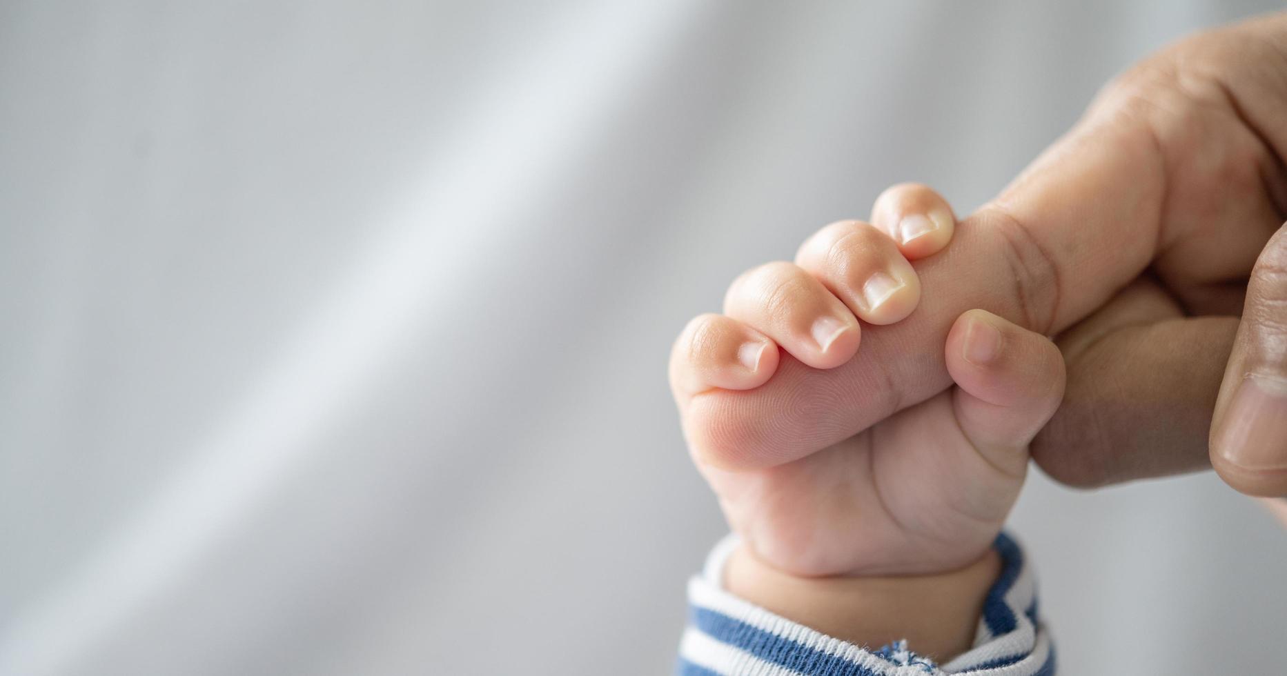 The hand of the newborn baby holds the fingers of the mother photo