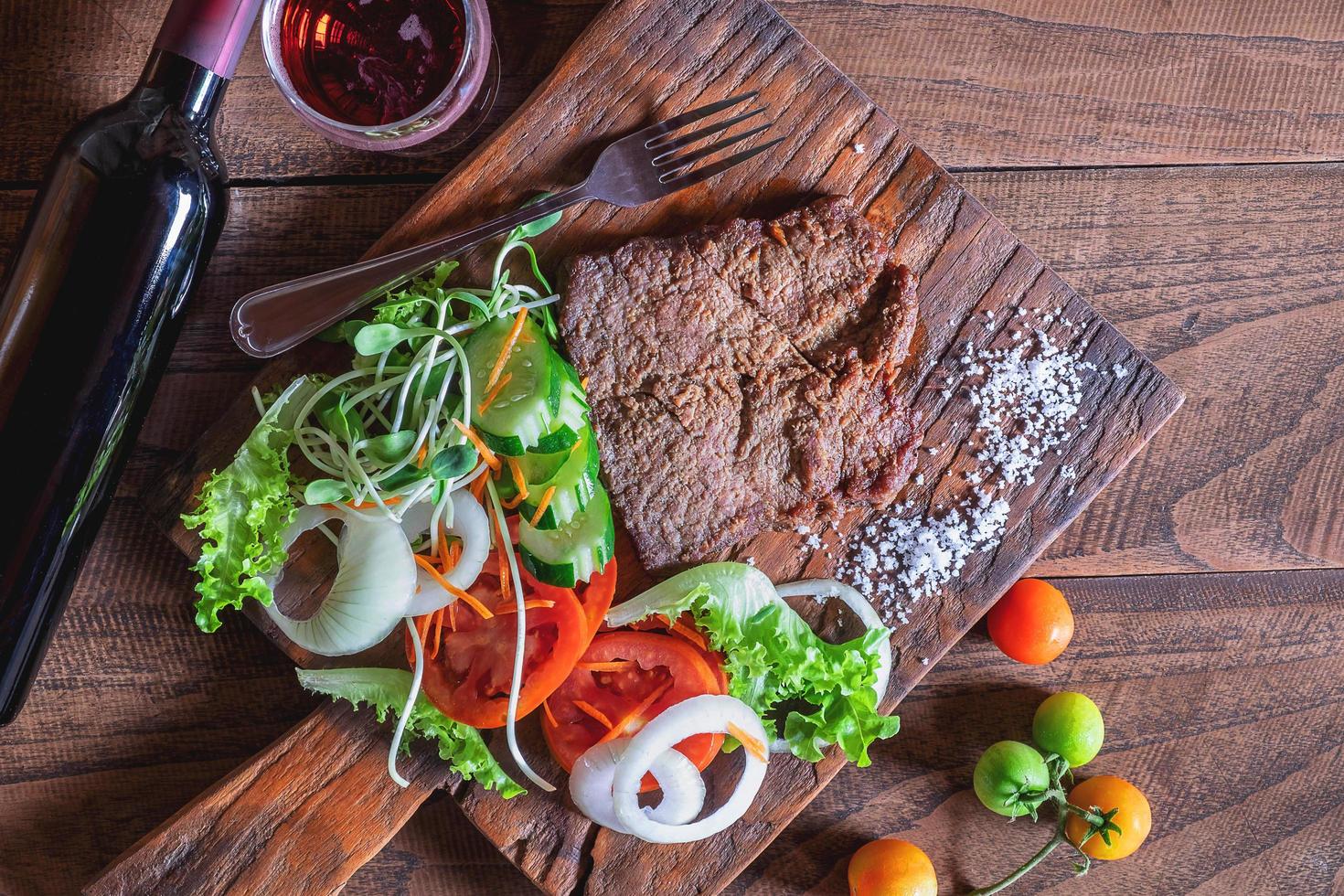 Filete de ternera a la parrilla y verduras sobre una tabla de cortar de madera foto