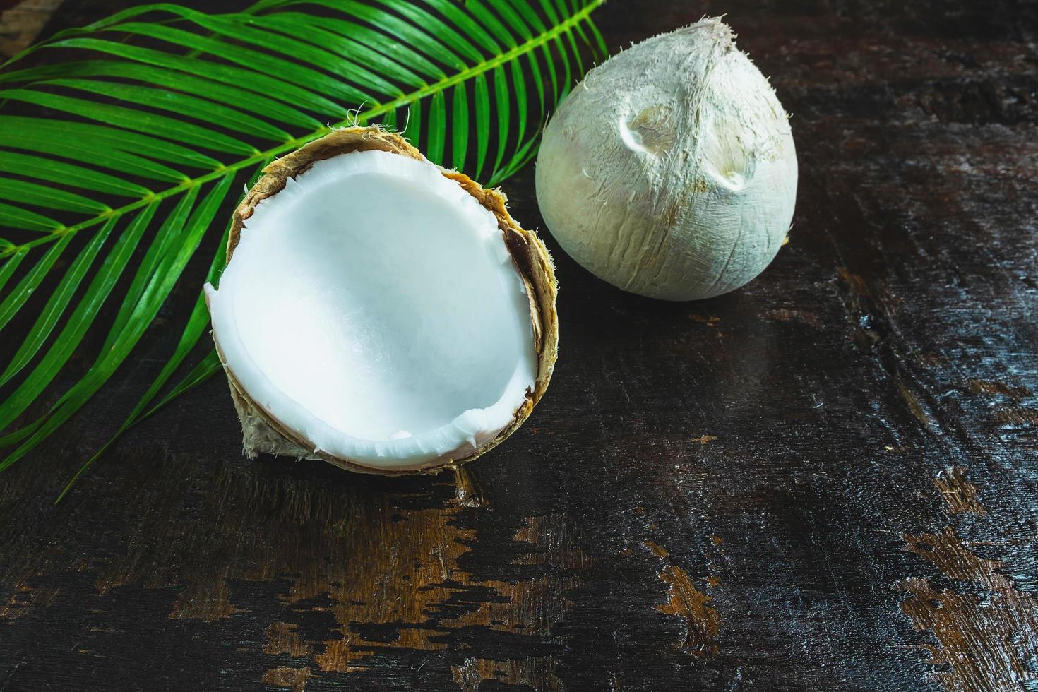Coconuts and a palm leaf on a wooden background photo