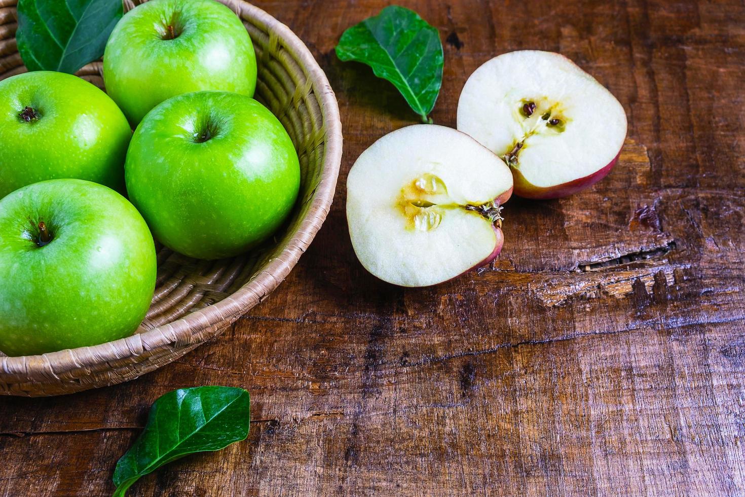 Manzanas verdes en una canasta sobre una mesa de madera foto