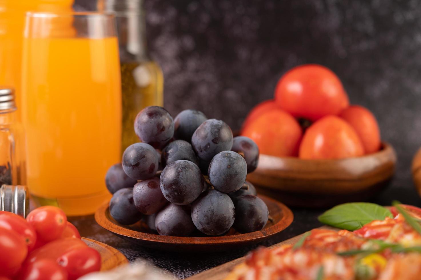 Black grapes with tomatoes orange juice and pizza photo