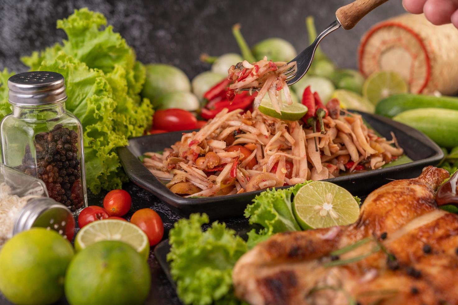 Thai papaya salad surrounded by vegetables and chicken photo