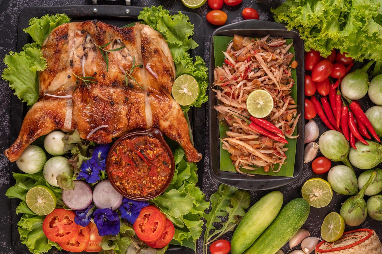 Thai papaya salad surrounded by vegetables and chicken photo