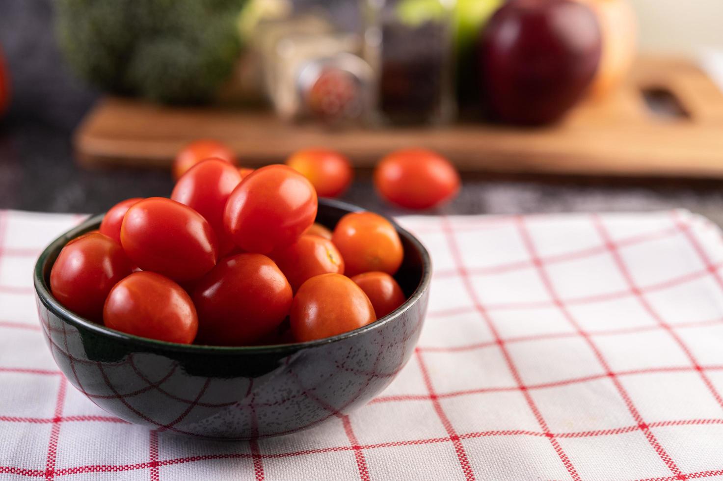 Tomates maduros frescos sobre una tela escocesa roja foto