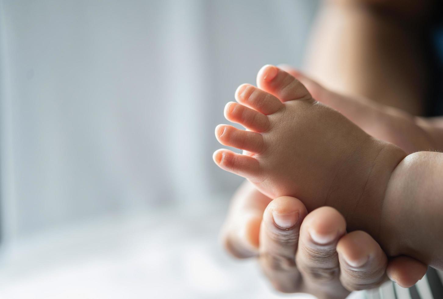 Mothers' hands holding baby feet photo