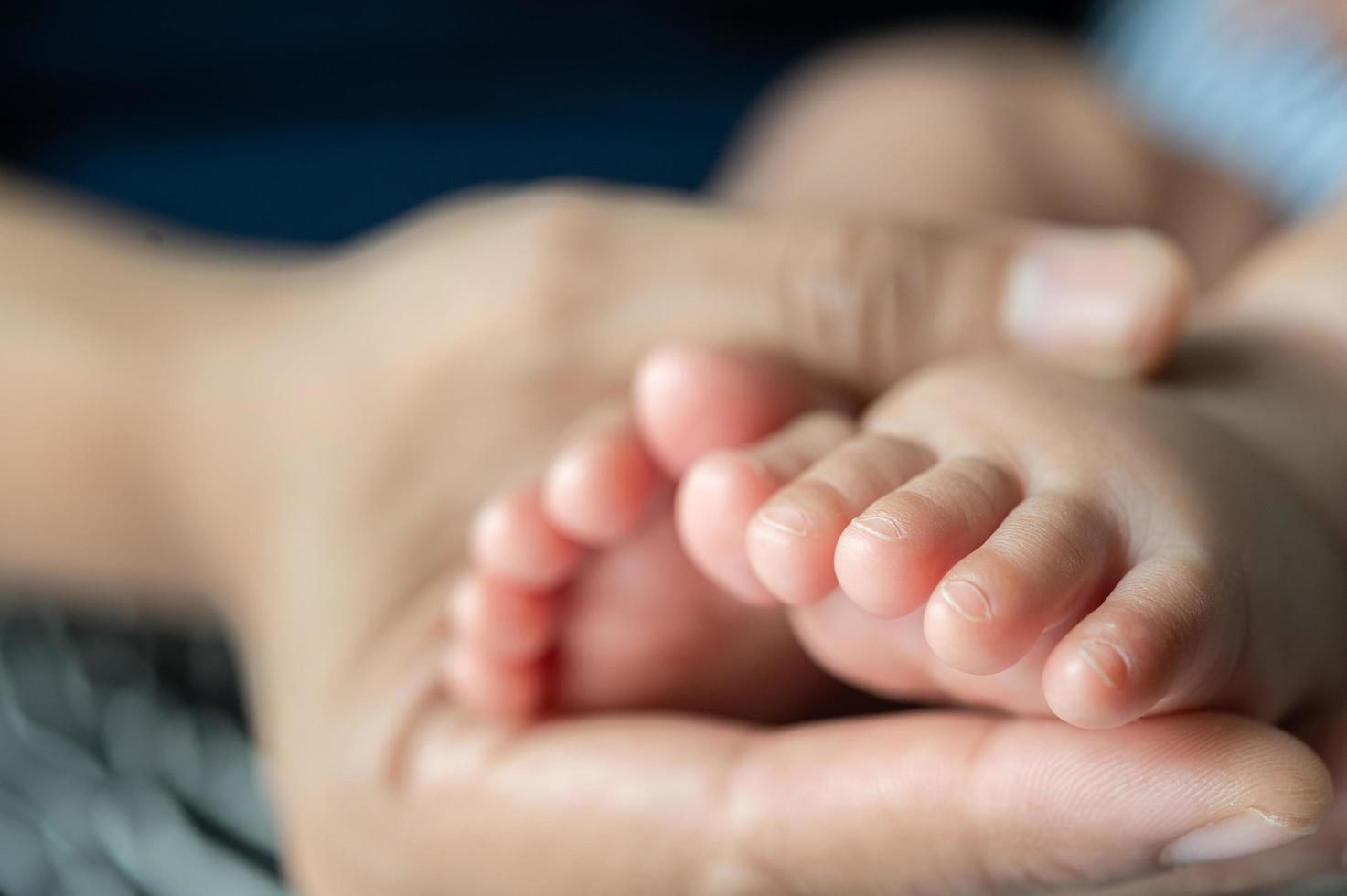 manos de las madres sosteniendo los pies del bebé foto