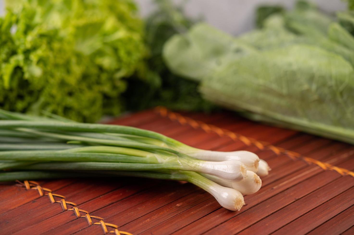 Spring onions placed on a wooden mat photo