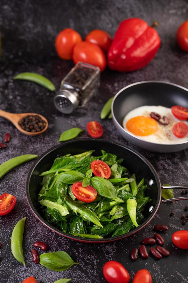 col rizada salteada en una cacerola con tomates y pimientos foto