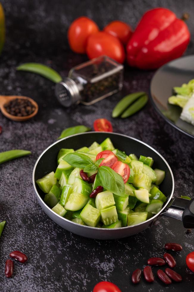 Cucumbers stir-fried with tomatoes in a frying pan photo