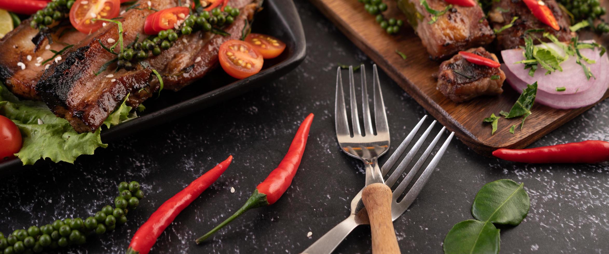 Two forks with chili and kaffir lime on a black background photo