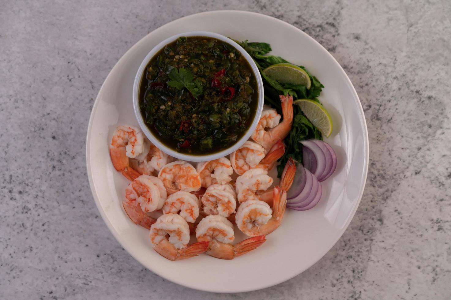 Flat lay of cooked prawns with dip photo