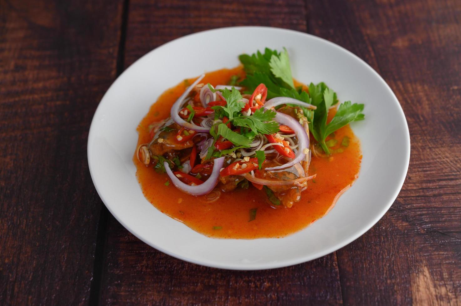 Spicy sardine salad on a dark wood table photo